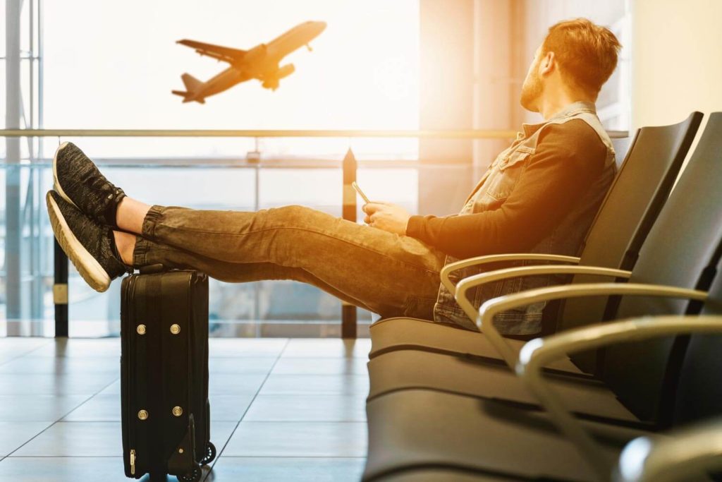 Man watches plane takeoff from gate.